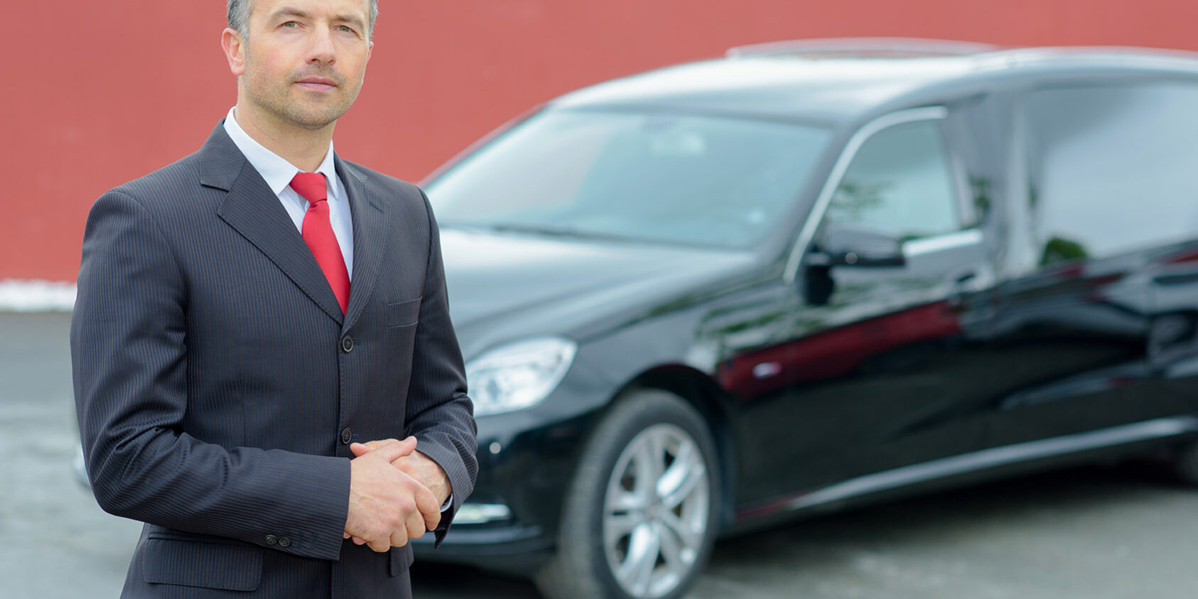 Hearse sales with a man in suit standing next to a hearse Hearse sales with a man in suit standing next to a hearse