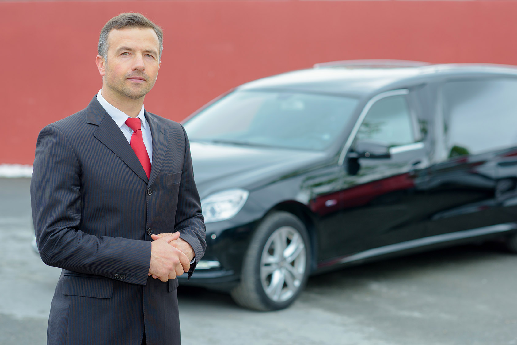 Hearse sales with a man in suit standing next to a hearse