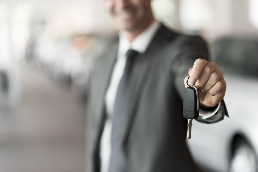 A salesperson holds out limo keys.