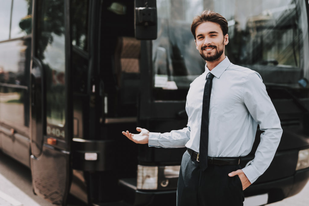 Smiling businessman standing in front of executive bus