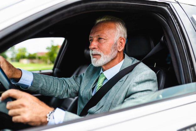 Man driving a white luxury limousine