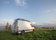 Mercedes sprinter van parked in a field with ladder roof rack and other accessories.
