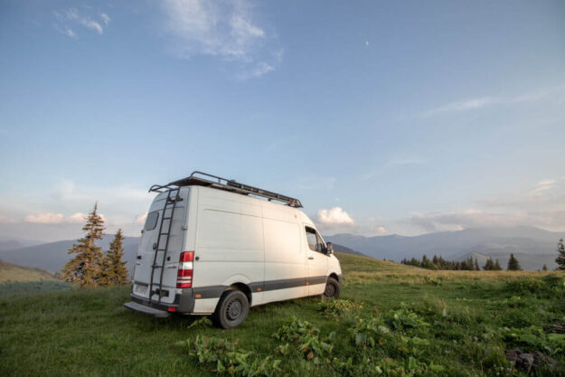 Mercedes sprinter van parked in a field with ladder roof rack and other accessories.