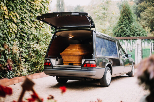 Photo,Of,A,Coffin,In,The,Back,Of,Car Hearse With Its Back Door Open