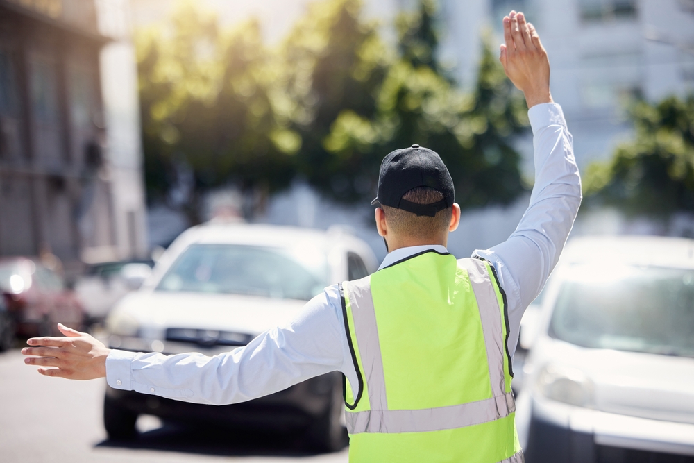 Traffic warden directing vehicles with raised arm and safety vest