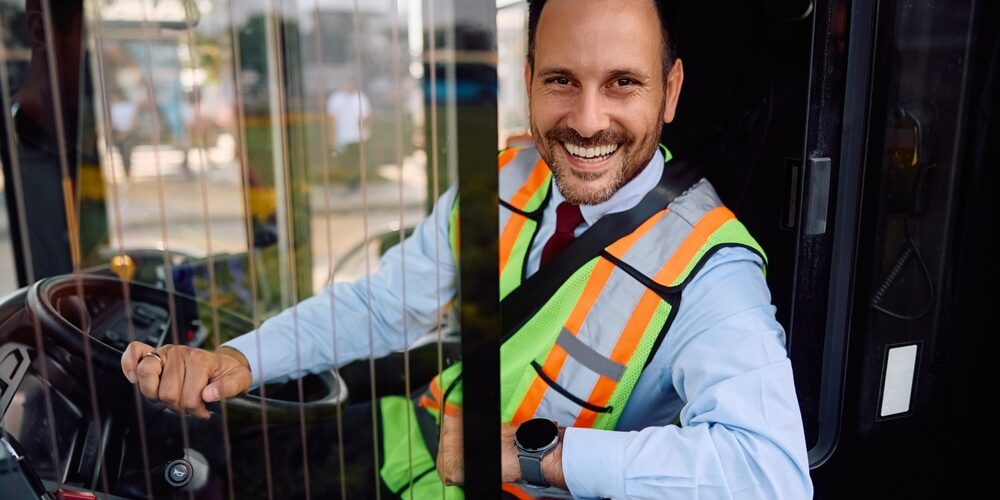 Friendly bus driver seated behind the wheel inside a coach vehicle