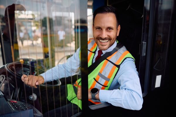 Friendly bus driver seated behind the wheel inside a coach vehicle