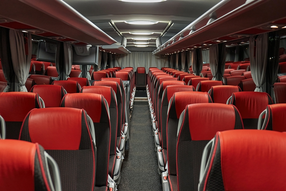 Interior of an empty coach bus with rows of red and black seats