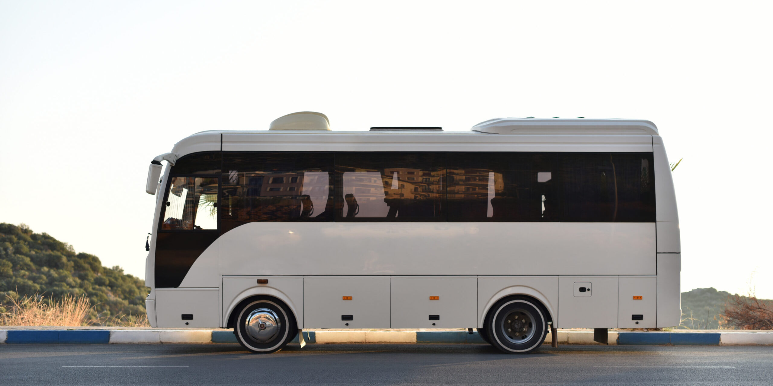 Coach bus parked on the side of the road with mountains in the background Coach bus parked on the side of the road with mountains in the background