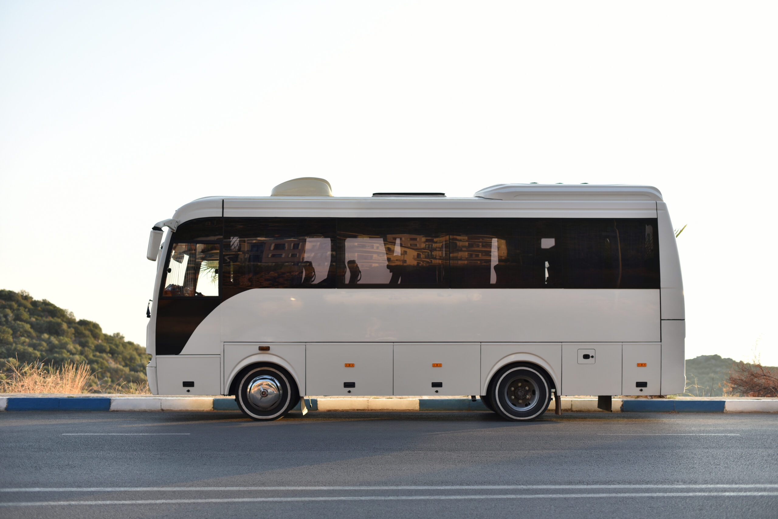 Coach bus parked on the side of the road with mountains in the background Coach bus parked on the side of the road with mountains in the background