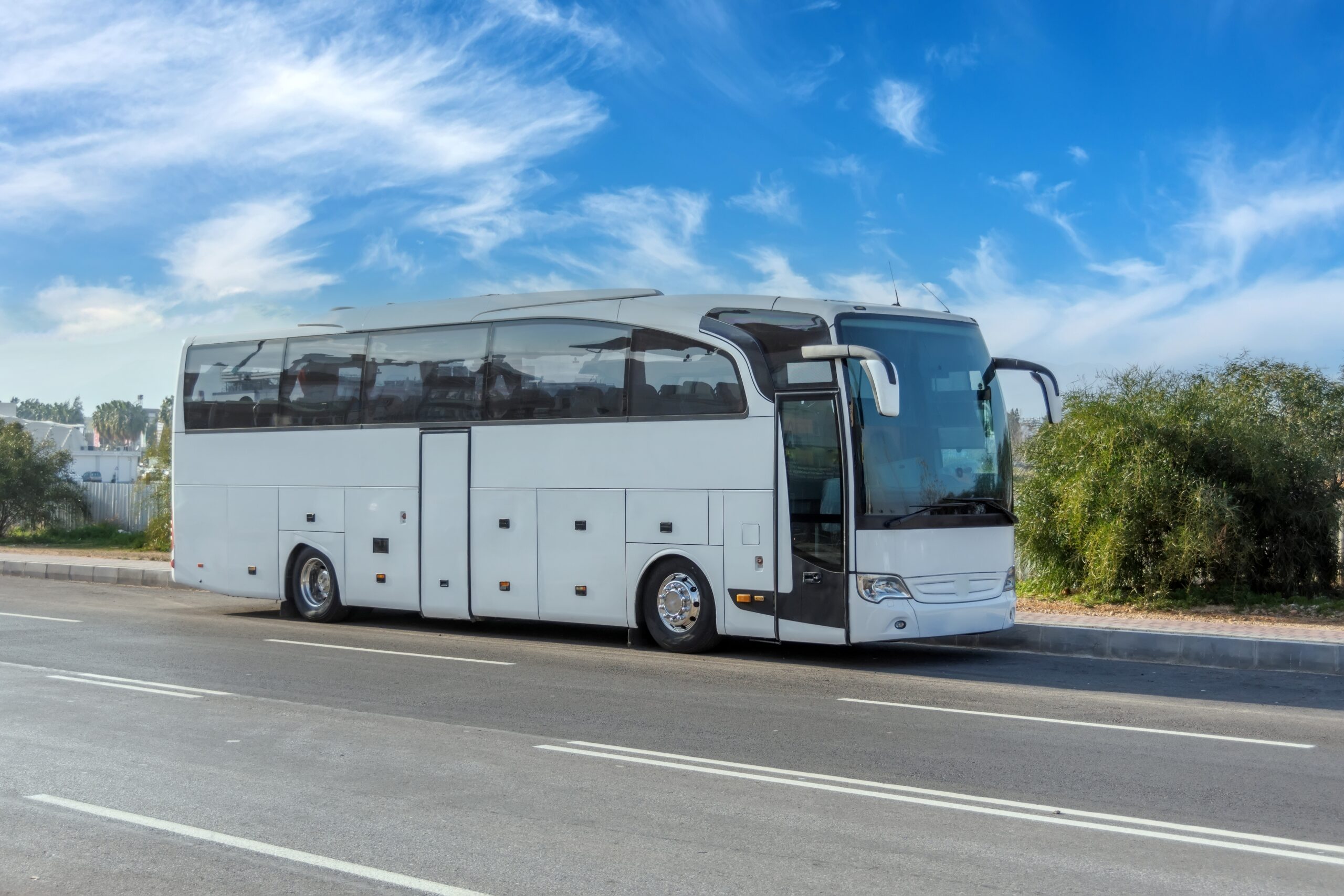 White Coach bus parked on the side of the road against a blue sky