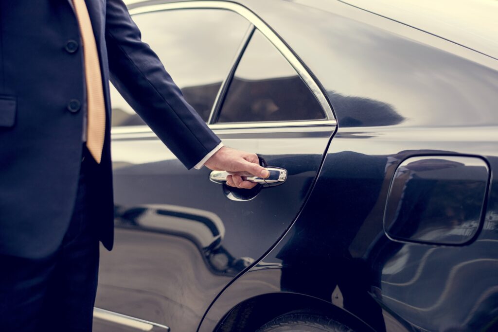 Businessman opening the door of a luxury SUV limousine