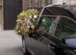 Hearse with a floral wreath in front of a church