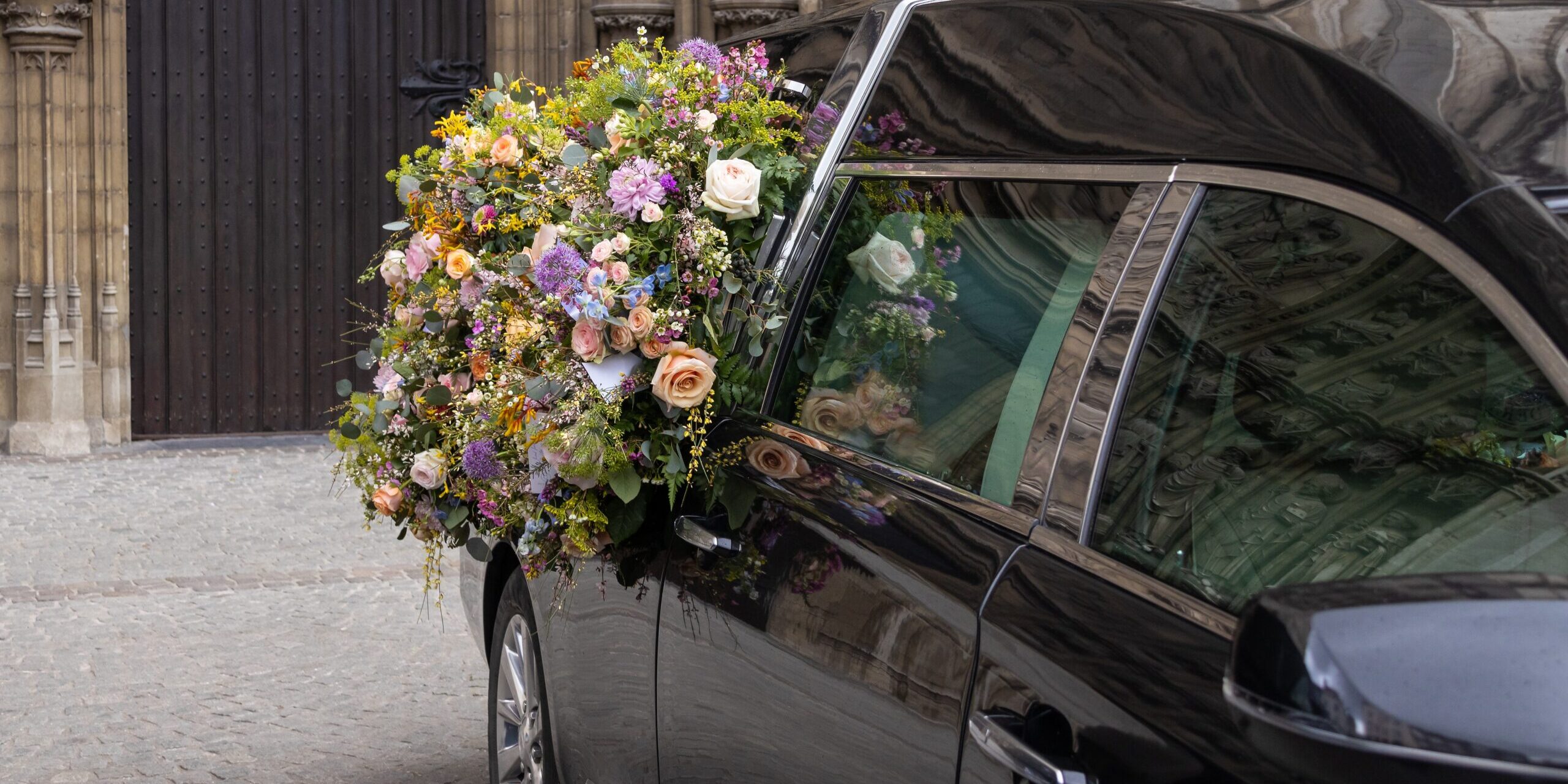Hearse with a floral wreath in front of a church