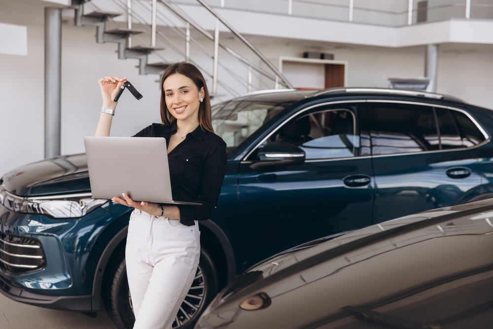 Smiling woman holding car keys and laptop