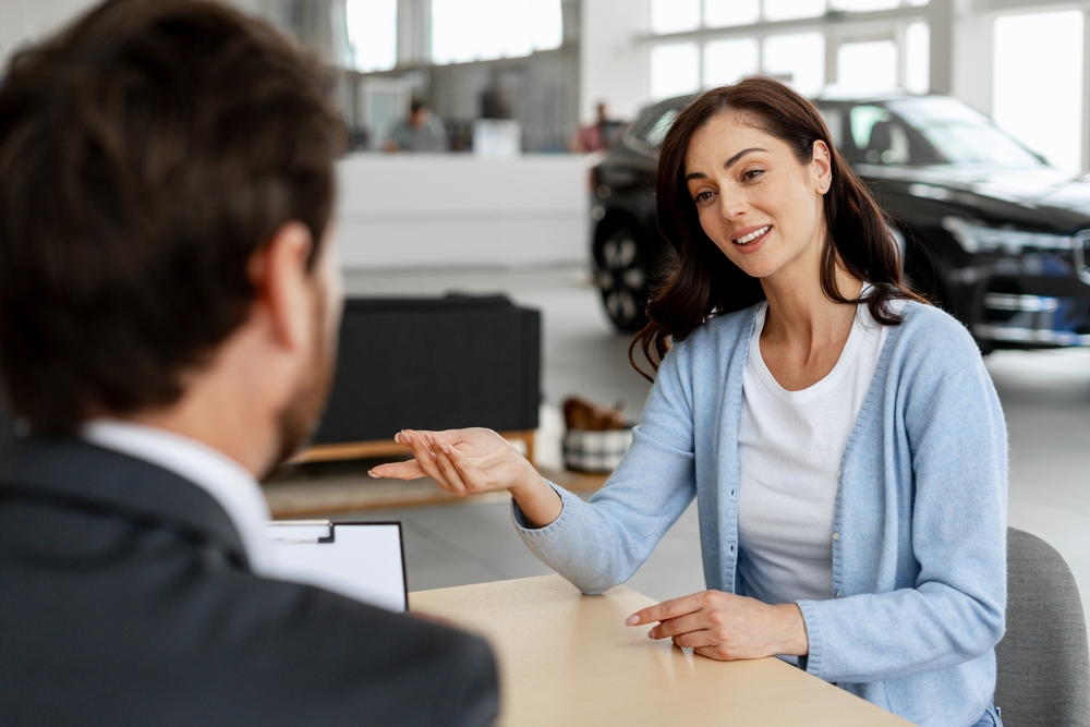 Woman speaking with a sales representative at a car dealership